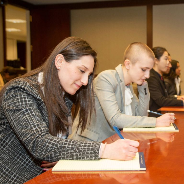 Pre-Law students writing on pad paper.