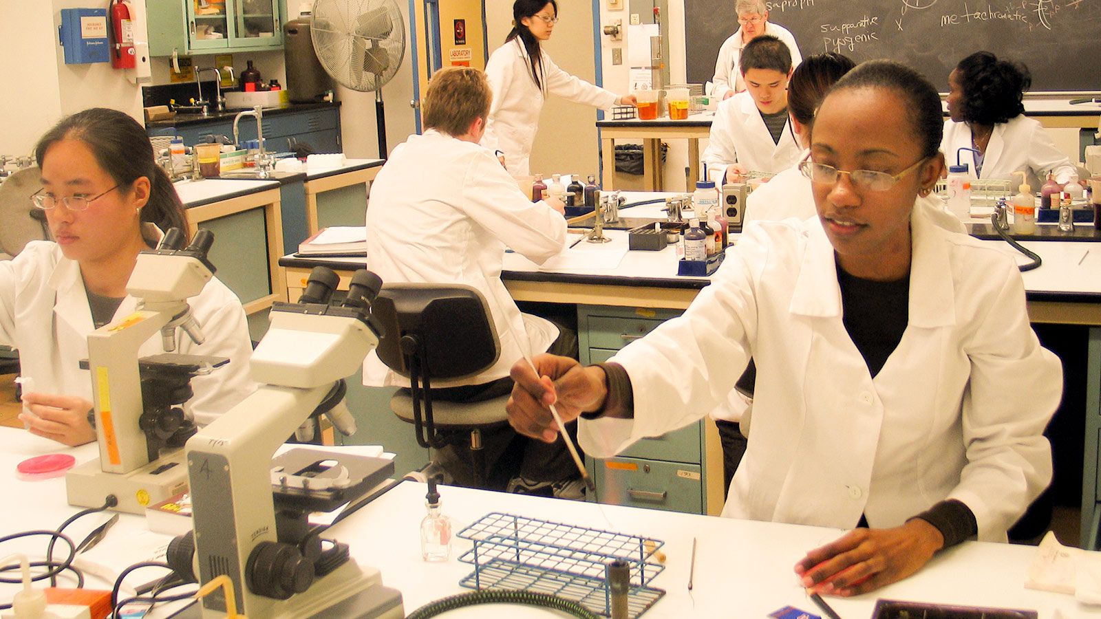 science lab class with students using microscopes at lab stations