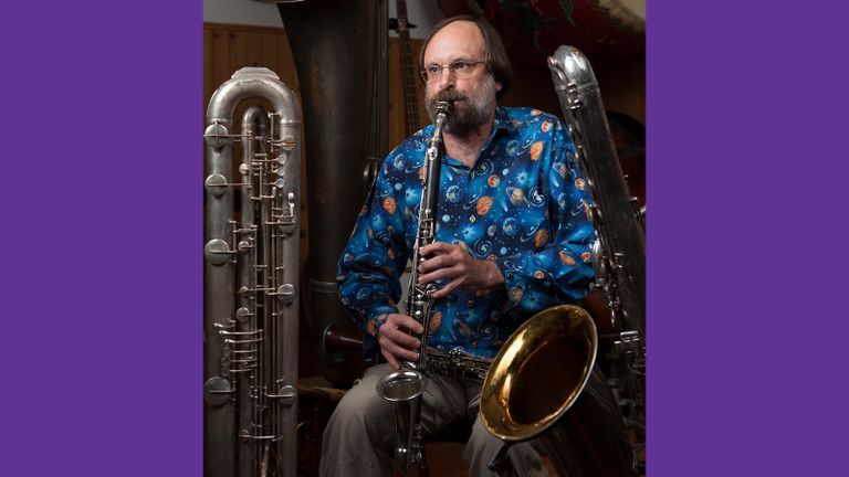 Photo of Scott Robinson in a galaxy print shirt playing the saxophone.