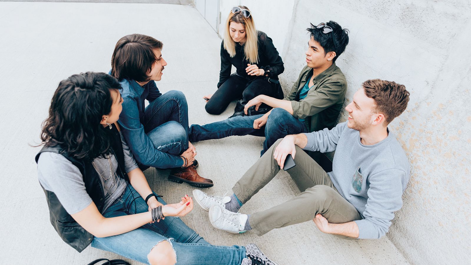 Photo - A group of students sitting and chatting with one student looking on. 