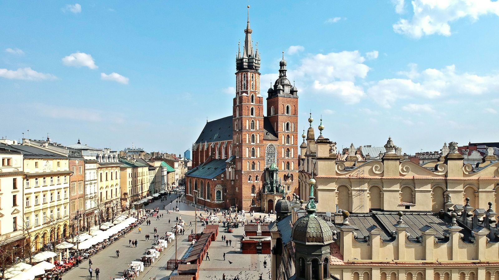 View of large red brick church and wide street with buildings in Krakow, Poland