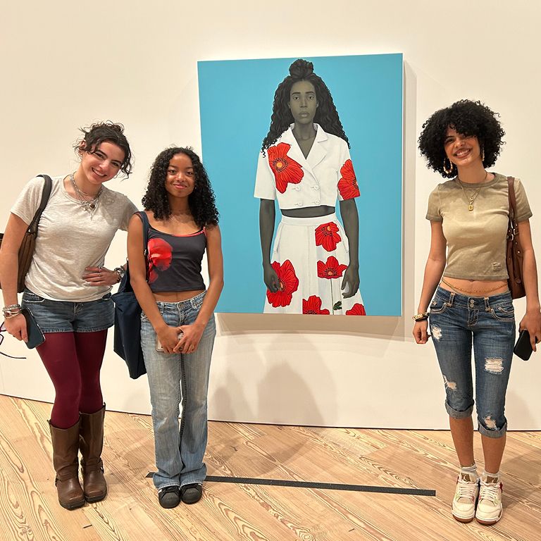 Student smile in front of a painting at the Whitney Museum.