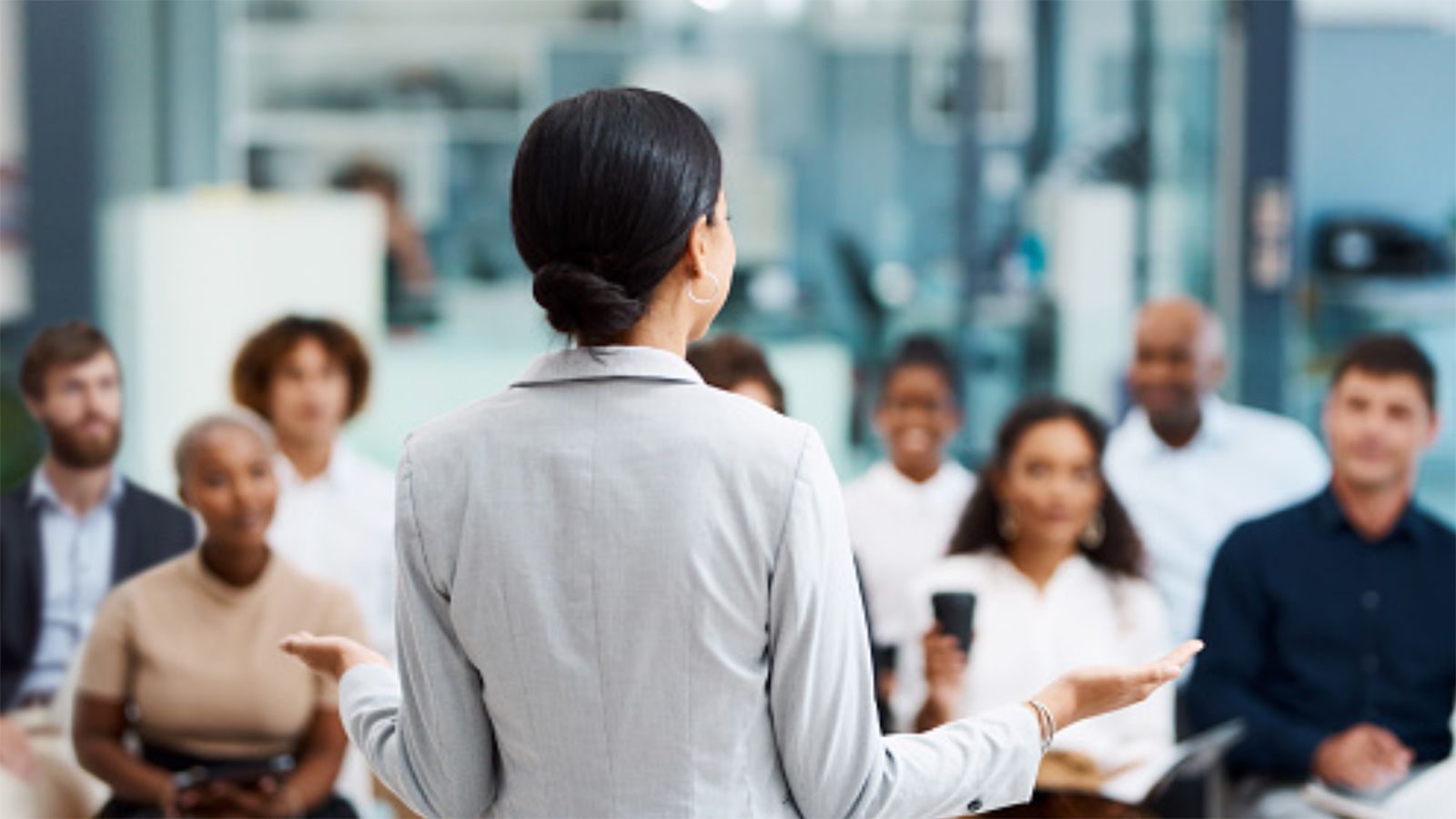 Photo - Young woman speaking to a group of students.