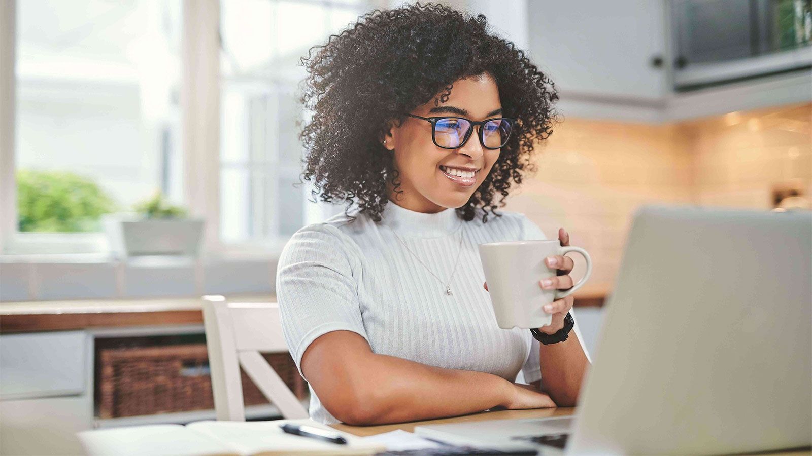 young woman at laptop holding mug